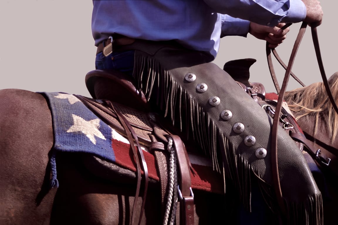 A cowboy is sitting on his horse with the american flag.