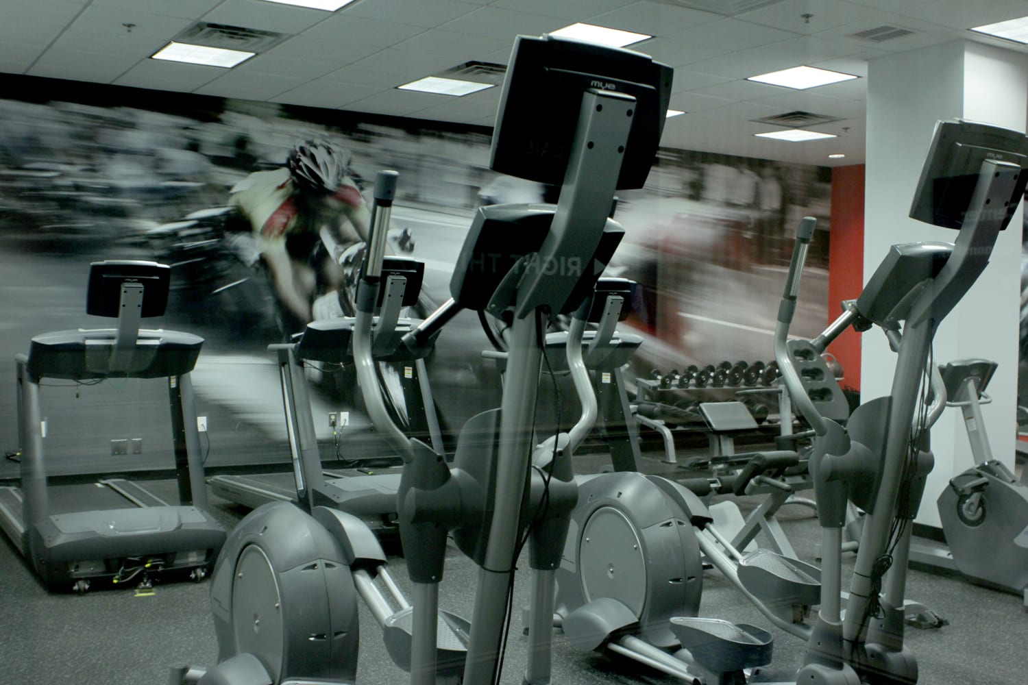 A gym with many machines and people in it
