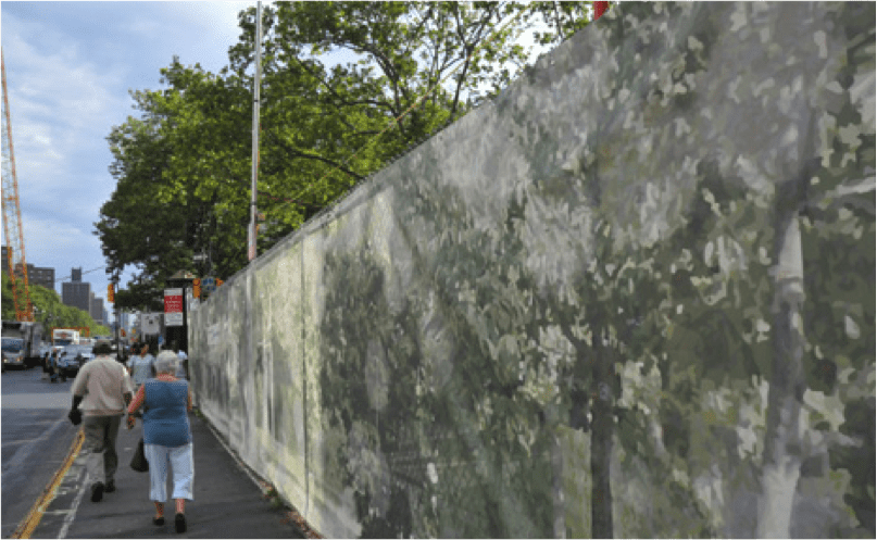 A person walking down the sidewalk near a wall.
