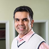 A man in a vest smiling for the camera.